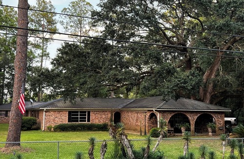 Moss Point House | Large fenced in home under a giant, moss covered, southern oak tree.